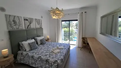 a bedroom with a bed and a table and a chandelier at Apartamento Magnólia in Lagos
