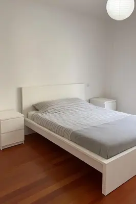 a white bedroom with a bed and two night stands at Seavale Apartement in Funchal