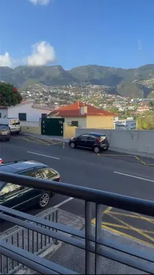 a black car driving down a street with mountains in the background at Seavale Apartement in Funchal