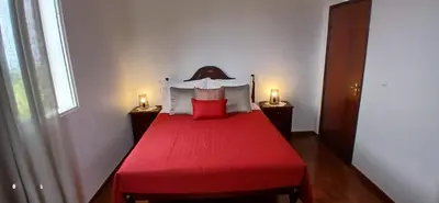 a bedroom with a red bed with two lights on the sides at Três Marias - Shared Countryside Connection in Lanceiros