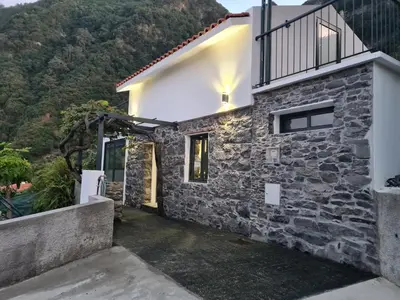 a stone house with a balcony on top of it at casa Farraia in Santana