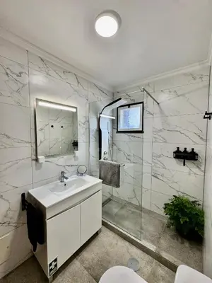 a white bathroom with a sink and a shower at StayinMachico in Machico