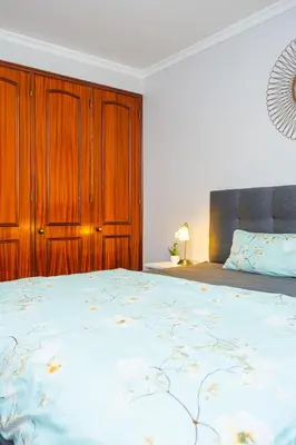 a bedroom with a large bed with a wooden cabinet at StayinMachico in Machico