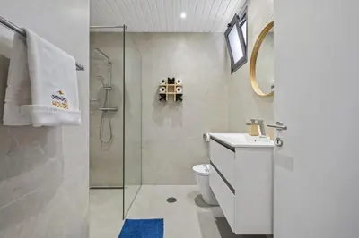 a bathroom with a toilet and a glass shower at Orinoco Sunset House II - Private Pool & Garden in Calheta
