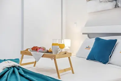a tray of food and glasses of orange juice on a bed at Orinoco Sunset House II - Private Pool & Garden in Calheta