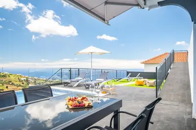 a view from the balcony of a house with a table and chairs at Orinoco Sunset House II - Private Pool & Garden in Calheta