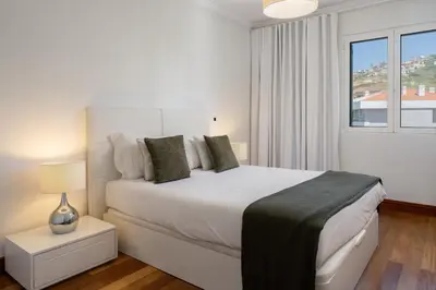 a white bedroom with a large bed and a window at Vila Formosa III by An Island Apart in Funchal