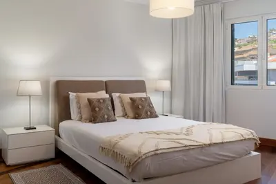 a white bedroom with a bed with pillows and a window at Vila Formosa III by An Island Apart in Funchal