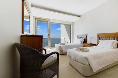 a bedroom with two beds and a chair and a window at Som do Mar Luxury Ocean Front Villa in Luz