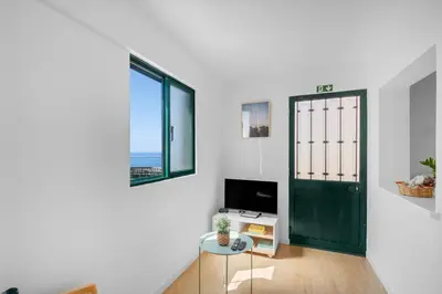 a living room with a green door and a tv at Luzia by the Sea - T1 Acolhedor a Passos da Praia in Calheta