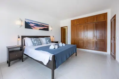 a bedroom with a large bed and a wooden closet at Apartment do Ramses in Luz