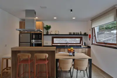 a kitchen with a wooden table and stools at Refúgio da Ribeira in São Vicente