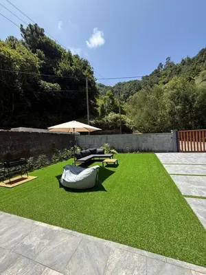 a lawn with an umbrella and a table and a bench at Refúgio da Ribeira in São Vicente
