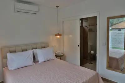 a bedroom with a bed with white pillows and a mirror at Refúgio da Ribeira in São Vicente