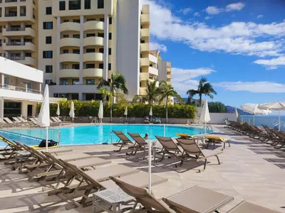 a swimming pool with lounge chairs and a hotel at Sente o mar da Ilha da Madeira in Funchal