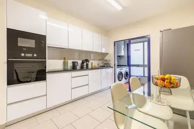 a kitchen with white cabinets and a glass table at Suite Vista Mar in Funchal
