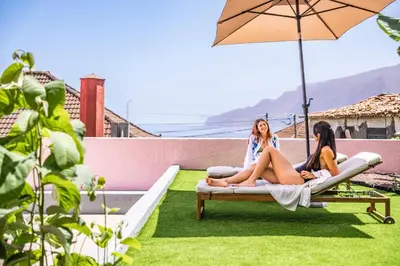 two girls sitting on a couch on a patio with an umbrella at Villa Rosa Mare by Homie in Seixal