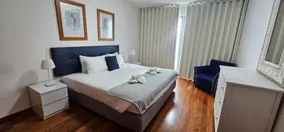 a bedroom with a large bed and a blue chair at Harbour View Apartment Free Parking in Funchal