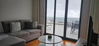 a living room with a couch and a table and a balcony at Harbour View Apartment Free Parking in Funchal