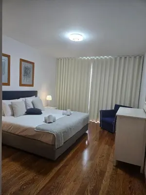 a bedroom with a large bed and a blue chair at Harbour View Apartment Free Parking in Funchal