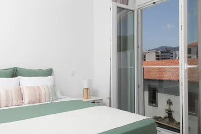 a white bedroom with a green and white bed at BJ Apartments Funchal in Funchal