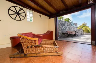 a wicker chair sitting in a room with a patio at Casa Leonor by Rent2U, Lda in Arco da Calheta