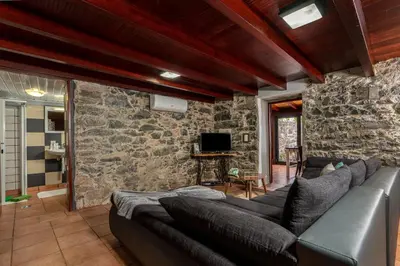 a living room with a couch and a stone wall at Casa Leonor by Rent2U, Lda in Arco da Calheta