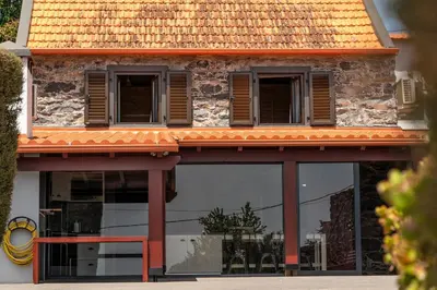 a building with glass windows and an orange roof at Casa Leonor by Rent2U, Lda in Arco da Calheta