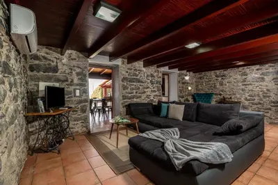 a living room with a couch and a stone wall at Casa Leonor by Rent2U, Lda in Arco da Calheta