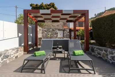 a patio with two chairs and a pergola at Casa Leonor by Rent2U, Lda in Arco da Calheta