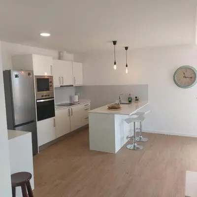 a kitchen with white cabinets and a clock on the wall at Paradise Point Sea & Mountain view in Estreito da Calheta