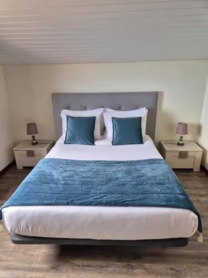 a bedroom with a large bed with blue pillows at North Coast View in Seixal