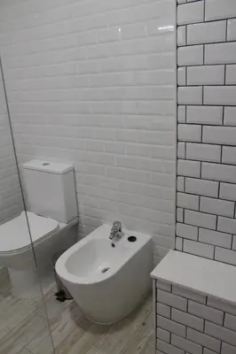 a white bathroom with a toilet and a bath tub at Beach front apartment 1 in Sagres