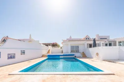 a villa with a swimming pool and an umbrella at Casa Dos Amigos in Budens