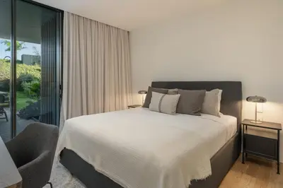 a bedroom with a white bed and a chair at Savoy Monumentalis IX by An Island Apart in Funchal