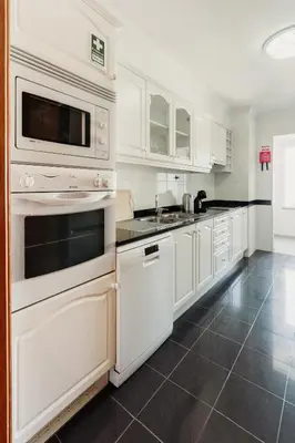 a white kitchen with white cabinets and appliances at Home By SG in Funchal