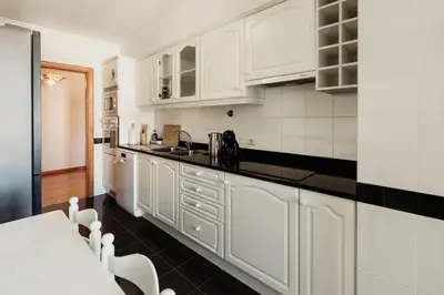 a kitchen with white cabinets and a black counter top at Home By SG in Funchal