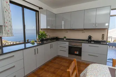 a kitchen with white cabinets and a view of the ocean at Vista al Mar in Ribeira Brava