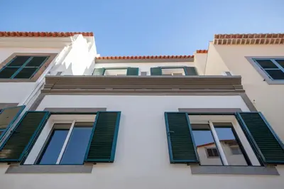 a white building with green shutters on it at Art House Funchalet in Funchal