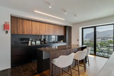 a kitchen with a bar with white stools at OceanView Pearl Varino by Holiday Rental Madeira in Funchal