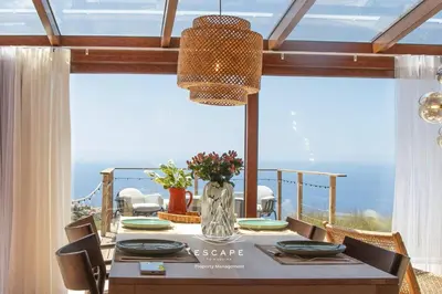 a patio with two chairs and an umbrella at Hilltop Hideaway by Escape to Madeira in Arco da Calheta