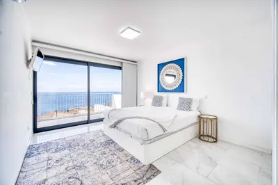a white bedroom with a bed and a large window at Casa dos Amores in Calheta