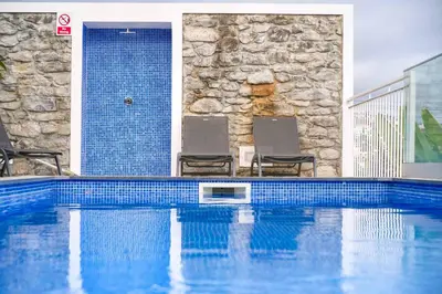 a swimming pool with two chairs in front of a building at Casa das Flores in Calheta