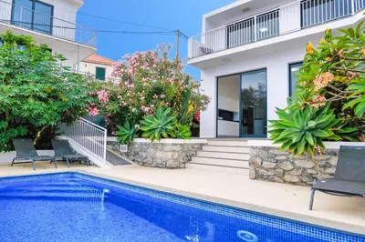 a villa with a swimming pool and a house at Casa das Flores in Calheta