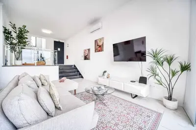 a white living room with a couch and a tv at Casa das Flores in Calheta