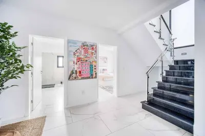 a white hallway with stairs and a painting on the wall at Casa das Flores in Calheta