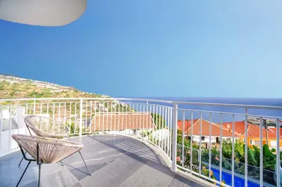 a balcony with a chair and a view of the ocean at Casa das Flores in Calheta