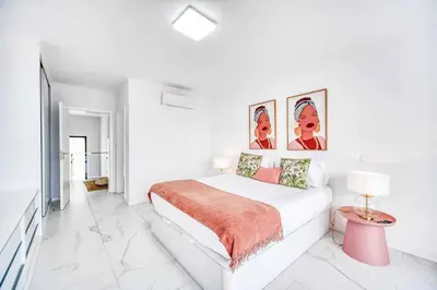 a white bedroom with a bed and a table at Casa das Flores in Calheta