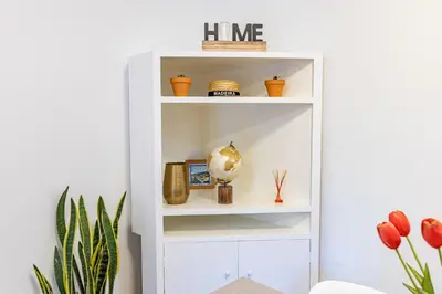 a white book shelf with plants in a room at Palm Tree by YOUR KEY in Caniço