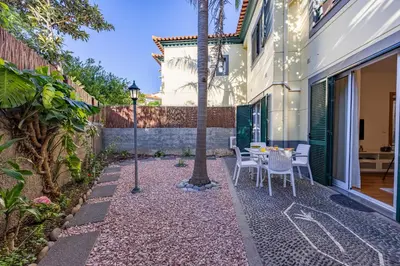 a patio with a table and chairs and a palm tree at Palm Tree by YOUR KEY in Caniço